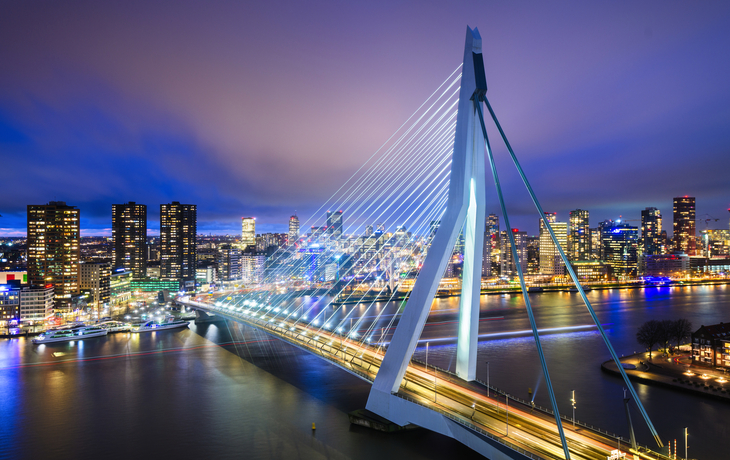 Erasmusbrücke in Rotterdam bei Nacht mit beleuchteter Skyline.