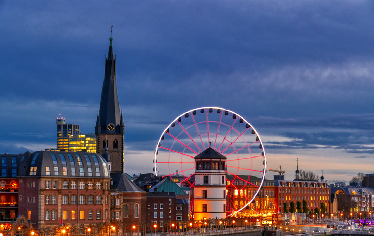 Schlossturm und beleuchtetes Riesenrad in Düsseldorf bei Abenddämmerung