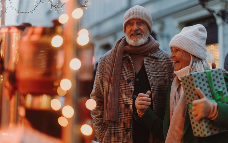 Älteres Paar beim Weihnachtseinkauf in einer geschmückten Stadtgasse.