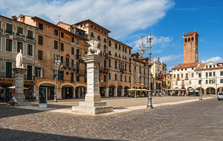 Historischer Platz mit Statuen und Turm bei Sonnenschein.