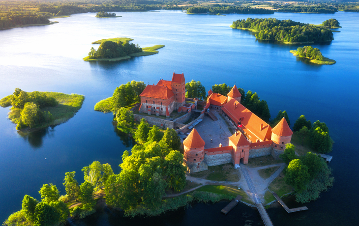 Luftaufnahme der Wasserburg Trakai in Litauen, umgeben von einem See.