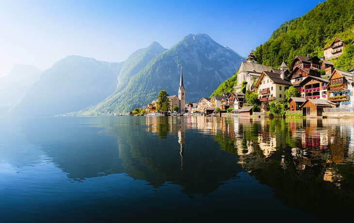 Bergdorf am See mit Kirche und Häusern im Sonnenschein.