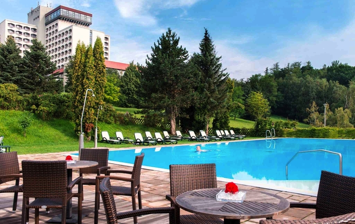 Außenpool mit Liegen im Ahorn Hotel Friedrichroda, umgeben von Bäumen.