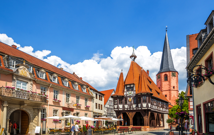 Historischer Marktplatz mit Fachwerkhaus und Kirche bei Sonnenschein.