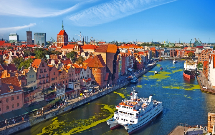 Panorama der Altstadt von Danzig mit Fluss und Booten bei klarem Himmel.