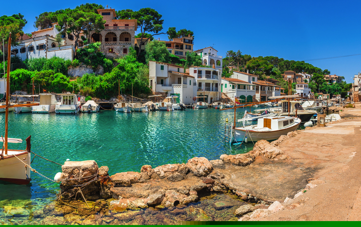 Mittelmeerhafen mit Booten und malerischen Gebäuden im Hintergrund.