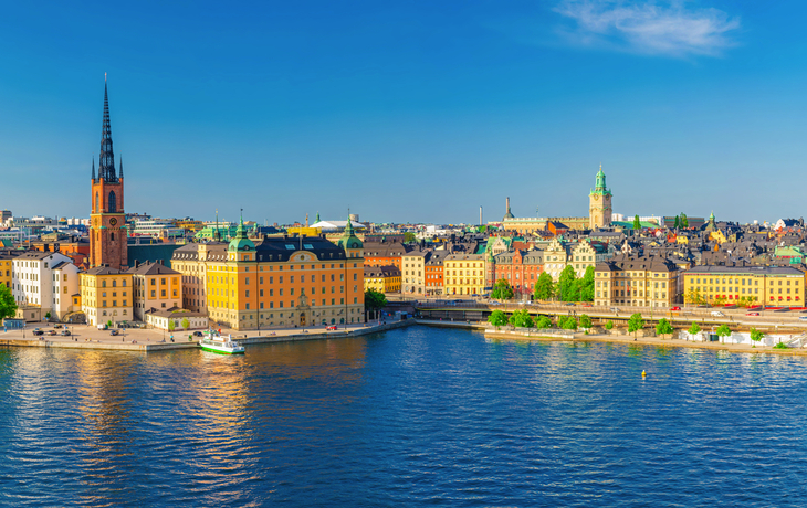 Panorama der Altstadt Stockholms mit Wasserfront und Kirchtürmen bei klarem Himmel.