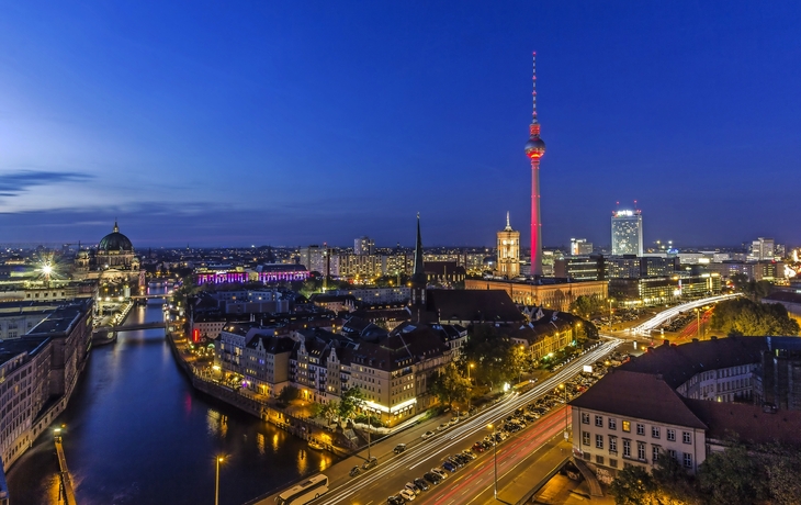 Blick auf die Berliner Skyline mit Dom und Fernsehturm bei Nacht, beleuchtet.