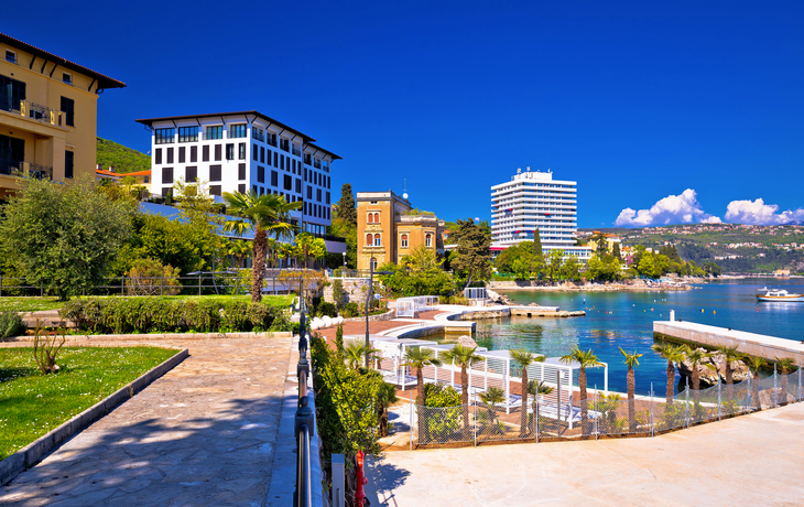 Küstenstadt mit Gebäuden, Promenade und klarem blauen Himmel.