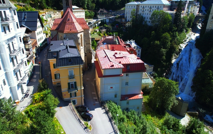Stadtansicht mit Wasserfall und historischen Gebäuden in bergiger Umgebung